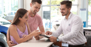 Salesman consulting young couple in car salon